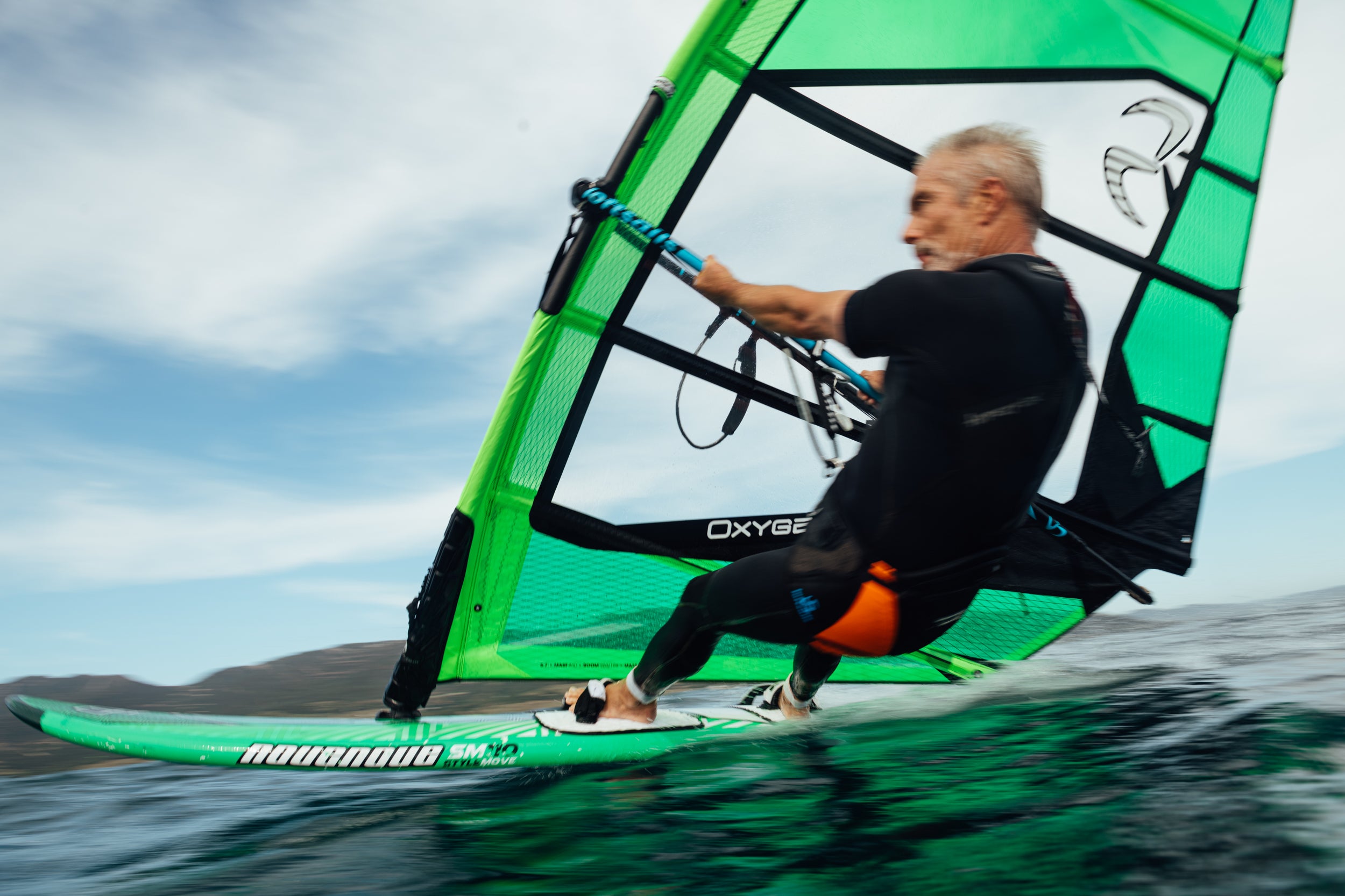 Monty Spindler windsurfing on a green sail with a blue sky background