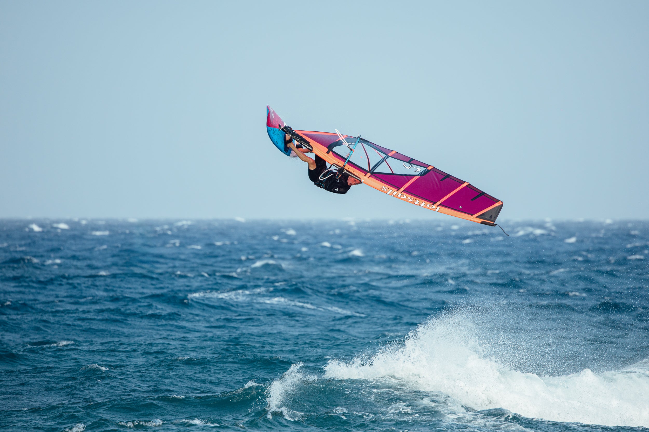 Person windsurfing in the ocean with a clear blue sky