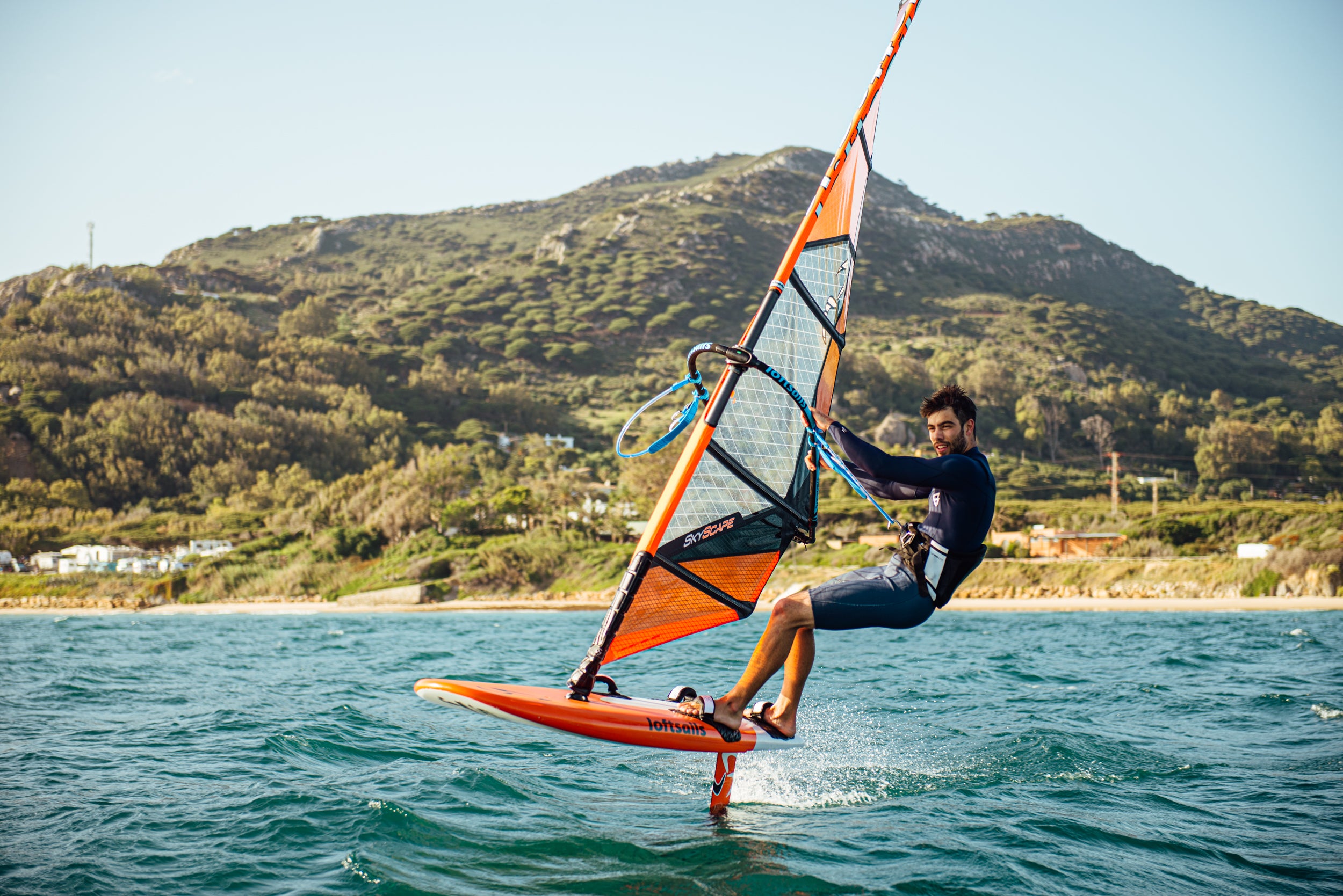 Person windsurfing on a body of water with mountains in the background