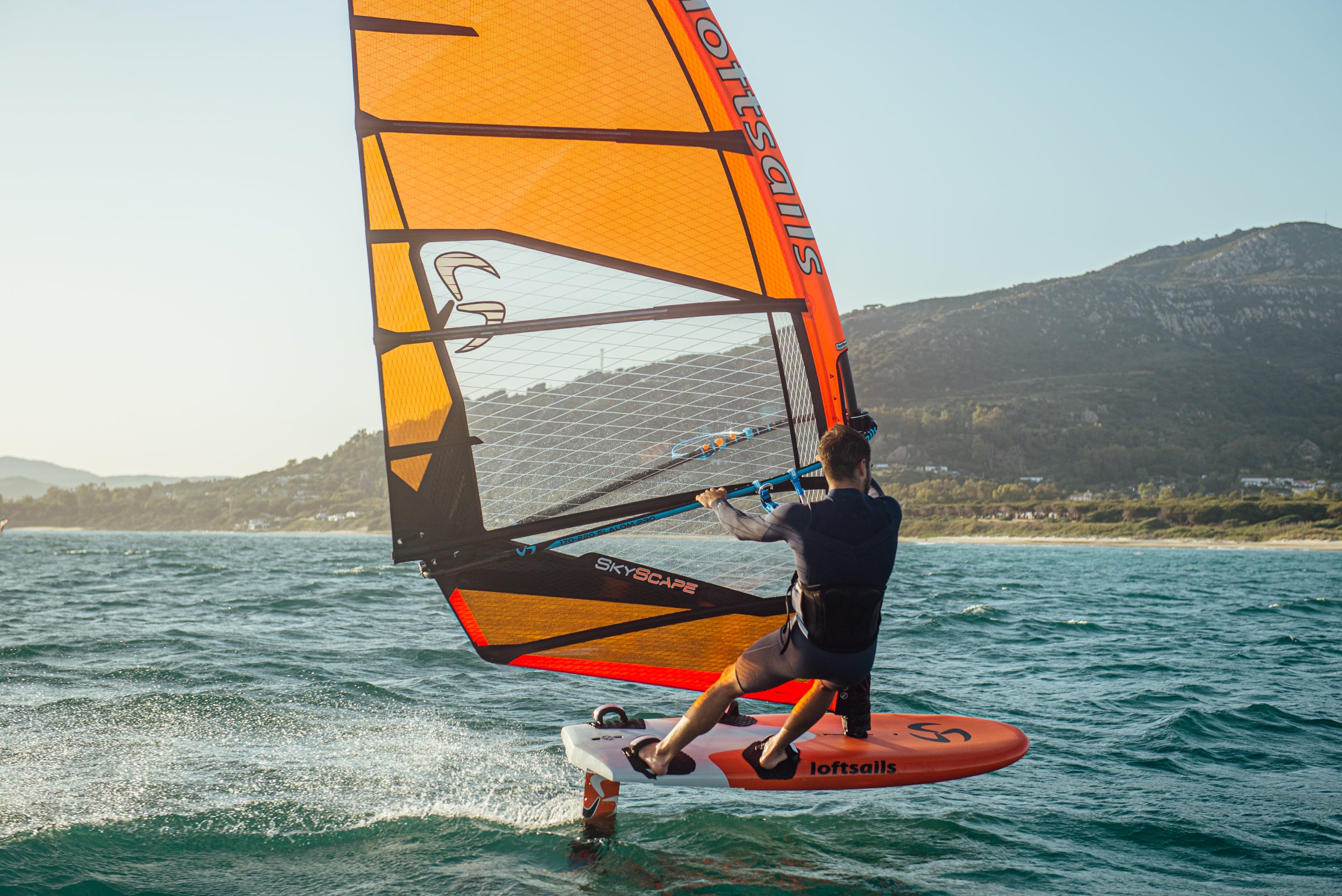 Person windsurfing on a body of water with mountains in the background