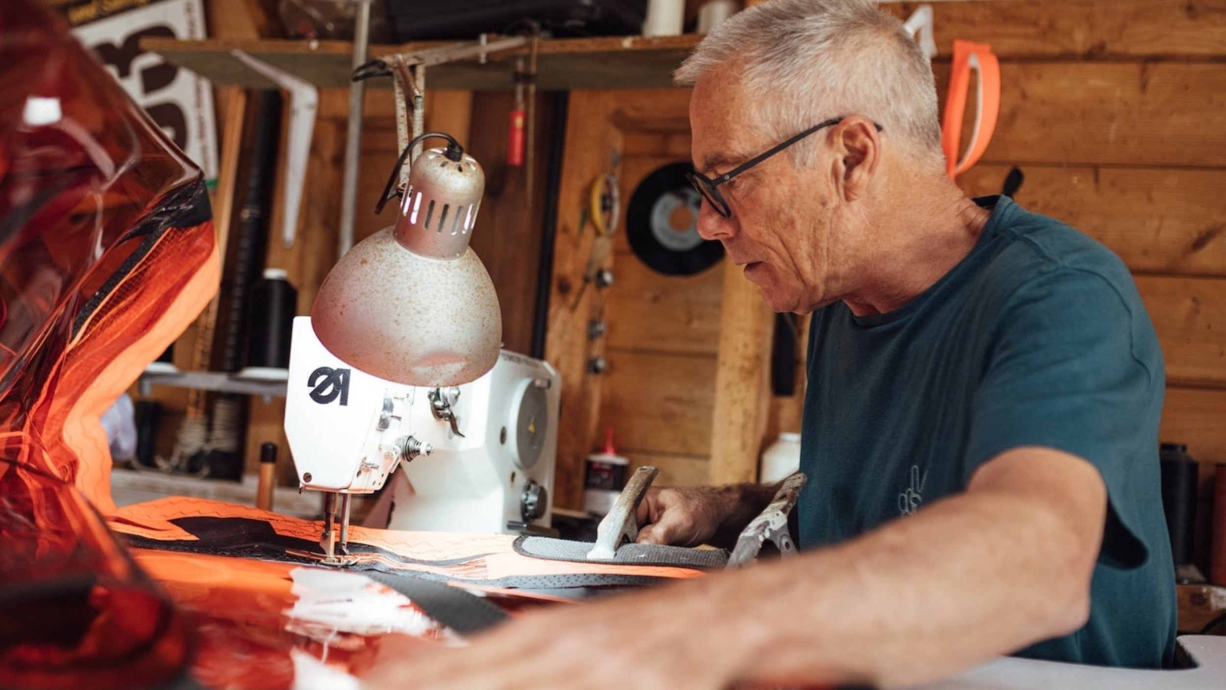 Man working on a sewing machine in a workshop with 'loftsails' branding.